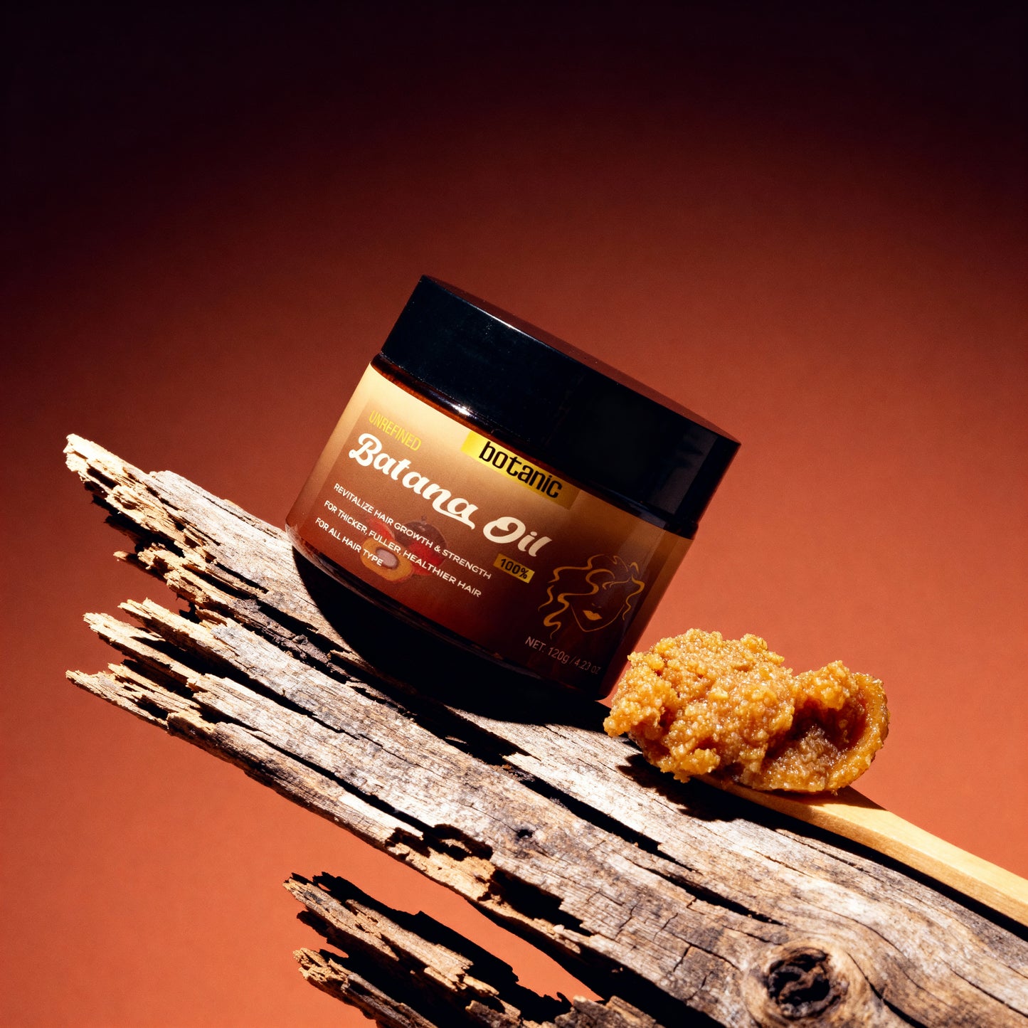 Jar of Balama Oil with a piece of oil on a wooden stick against a brown background