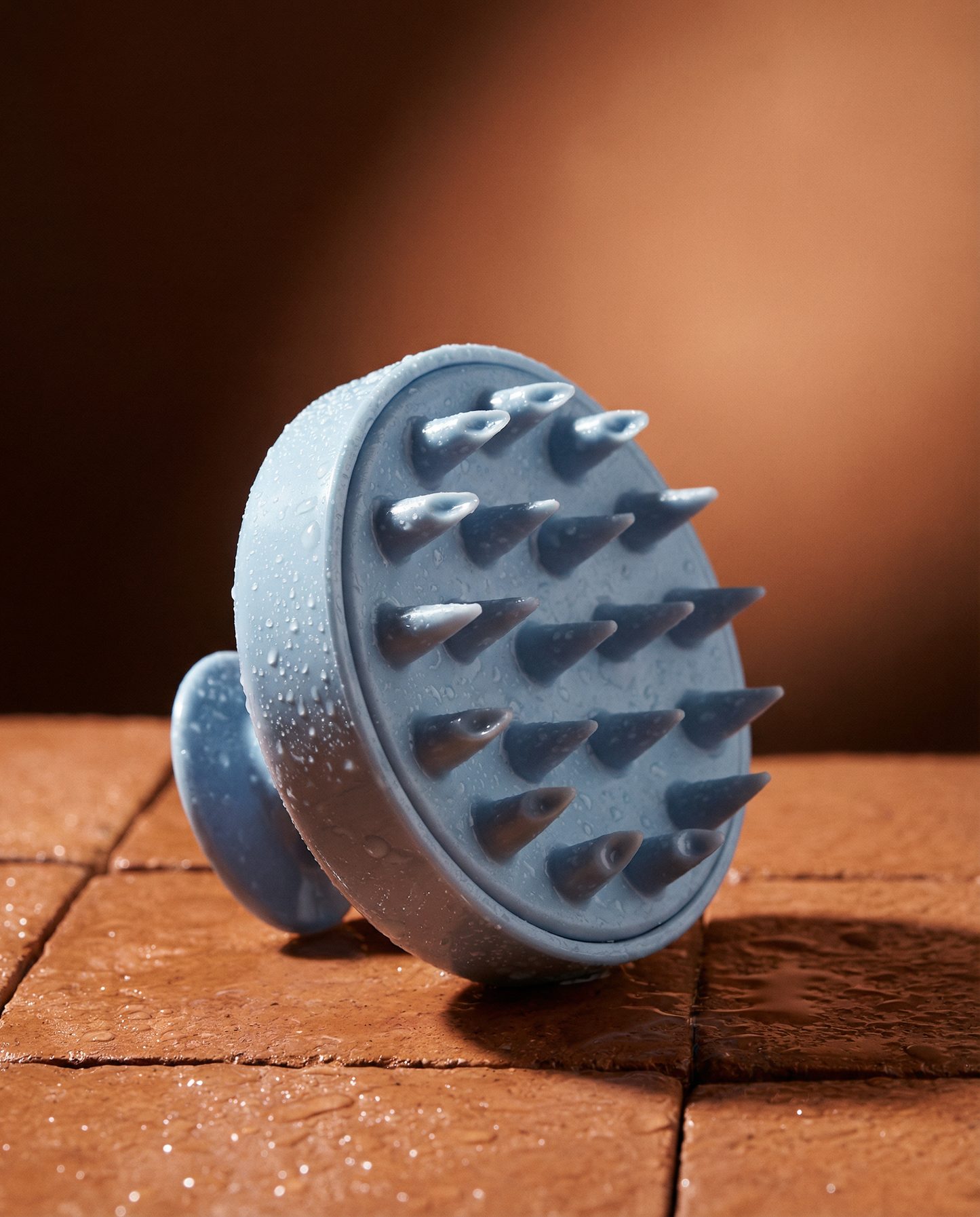 Blue silicone brush with textured surface on a wooden surface