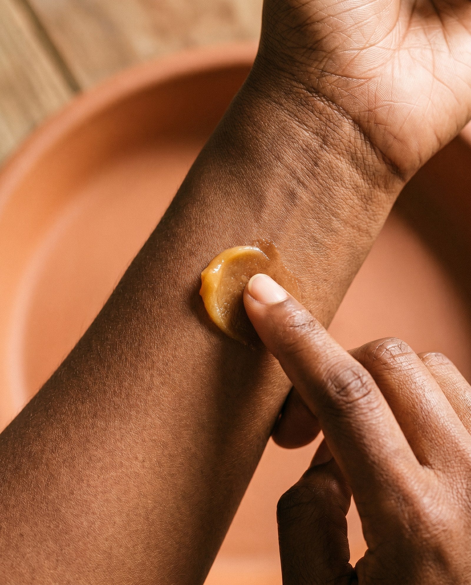 A single drop of amber botanical oil on the inside of a wrist